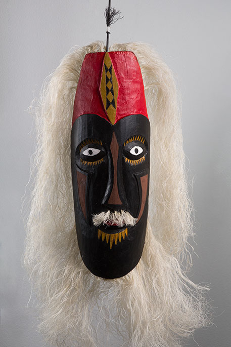 Cultural mask with brown, yellow ochre and red facial tones, and white wavy hair. - click to view larger image