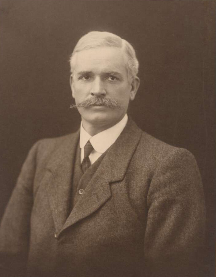 Faded, black and white studio portrait photo of silver-haired man with moustache. - click to view larger image