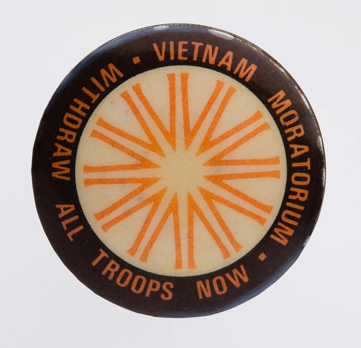 White, black and orange badge with the words Vietnam Moratorium/withdraw all troops now around the rim. - click to view larger image