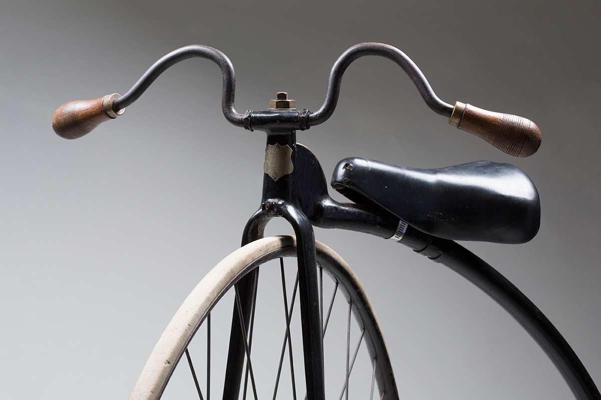 Image showing the top section of a penny-farthing bicylce, with the handlebars, saddle and part of the front wheel in frame. - click to view larger image