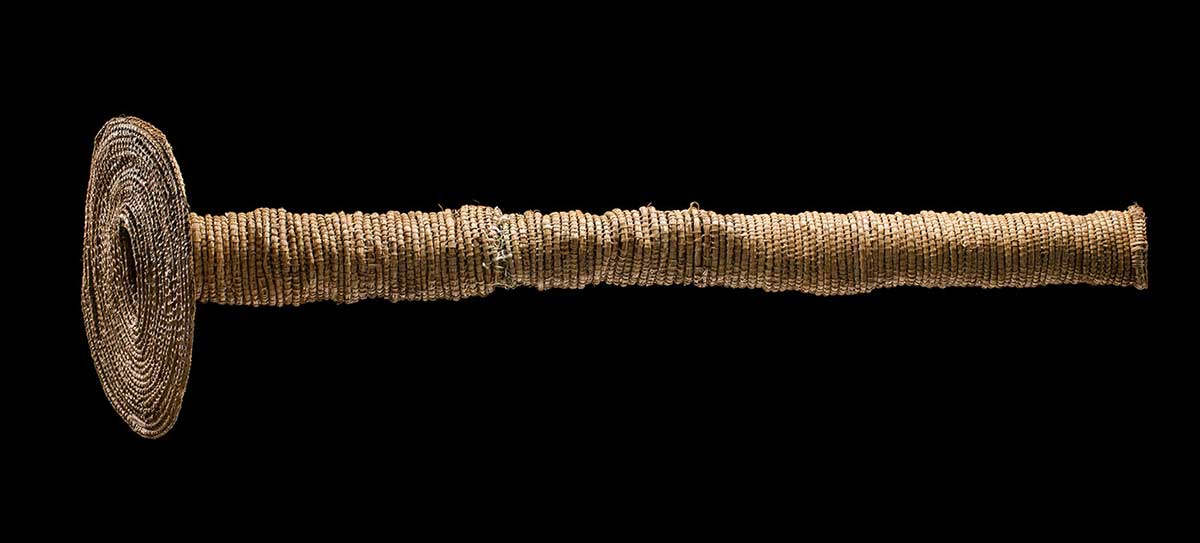 A woven eel trap consisting of a long tube attached to a disc shape with a central opening. - click to view larger image