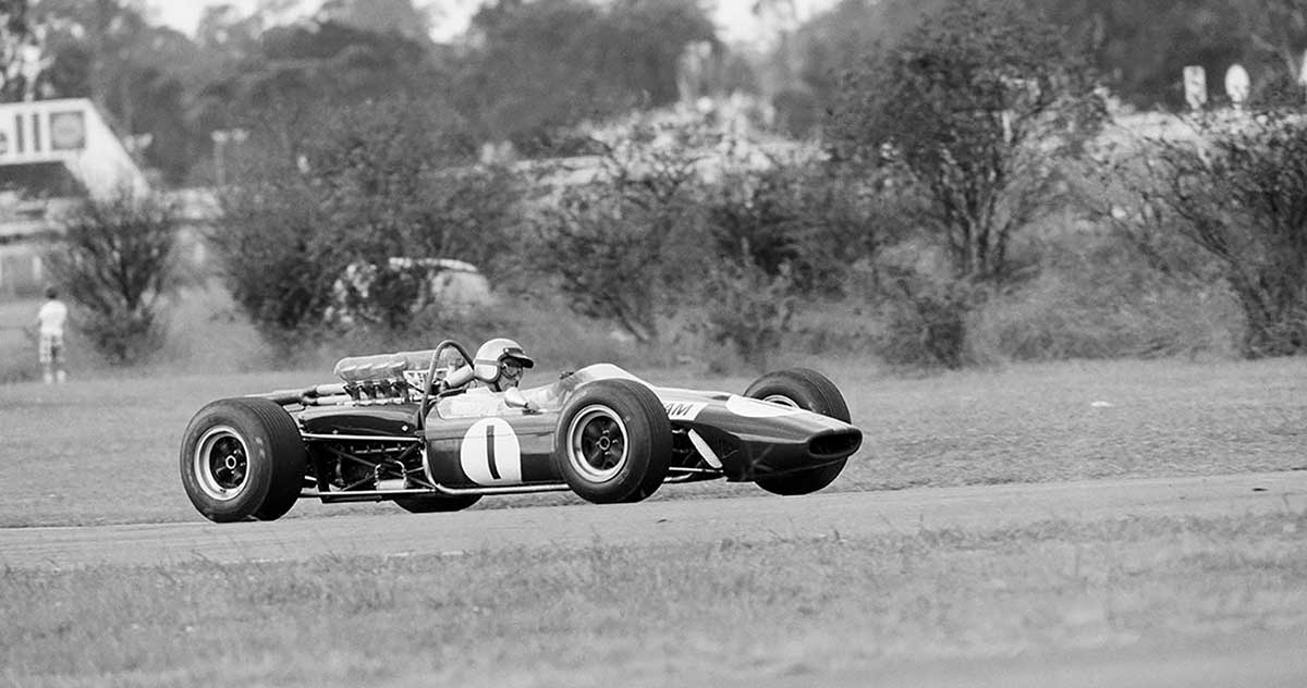 Black and white photograph of a racing car on racing track.