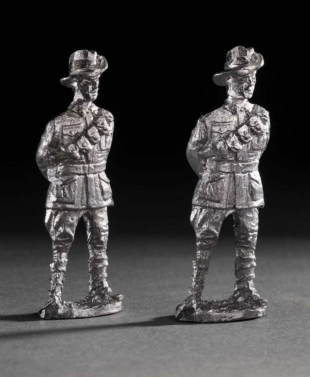 Metal figures of two Australian soldiers from World War 1 made from shrapnel recovered from French battlefields. It depicts two uniformed men standing with their legs apart and his hands clasped behind their back. - click to view larger image
