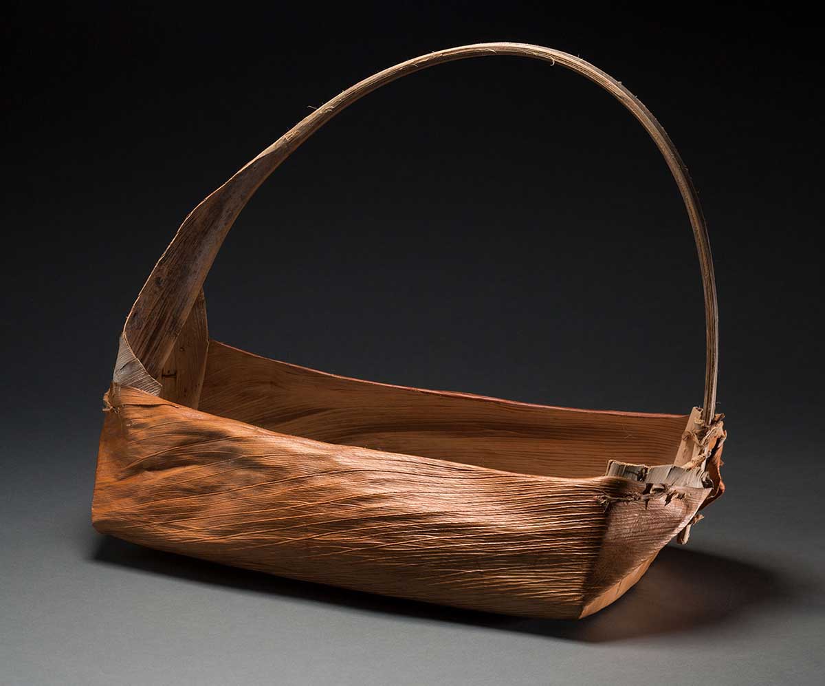 A long rectangular shaped basket with a handle made of natural fibres.