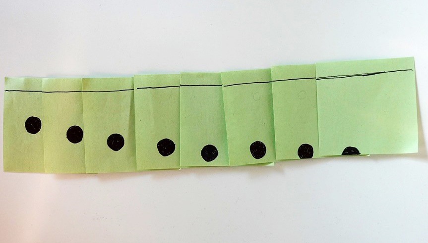 Series of green pieces of paper with black lines in the bottom section and black marks in the top section.