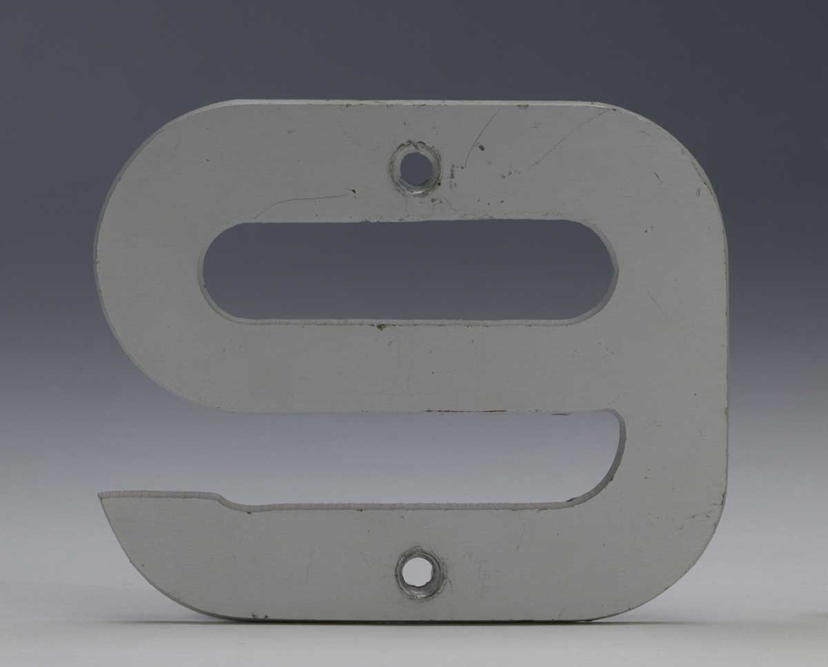 Studio photograph of a number nine made of metal. There are two holes for fixing with screws. - click to view larger image