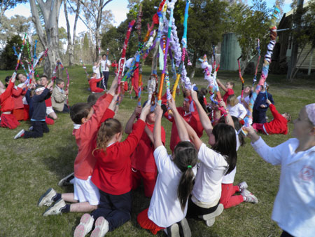 Groups of kneeling students holding fabric covered sticks in the air.