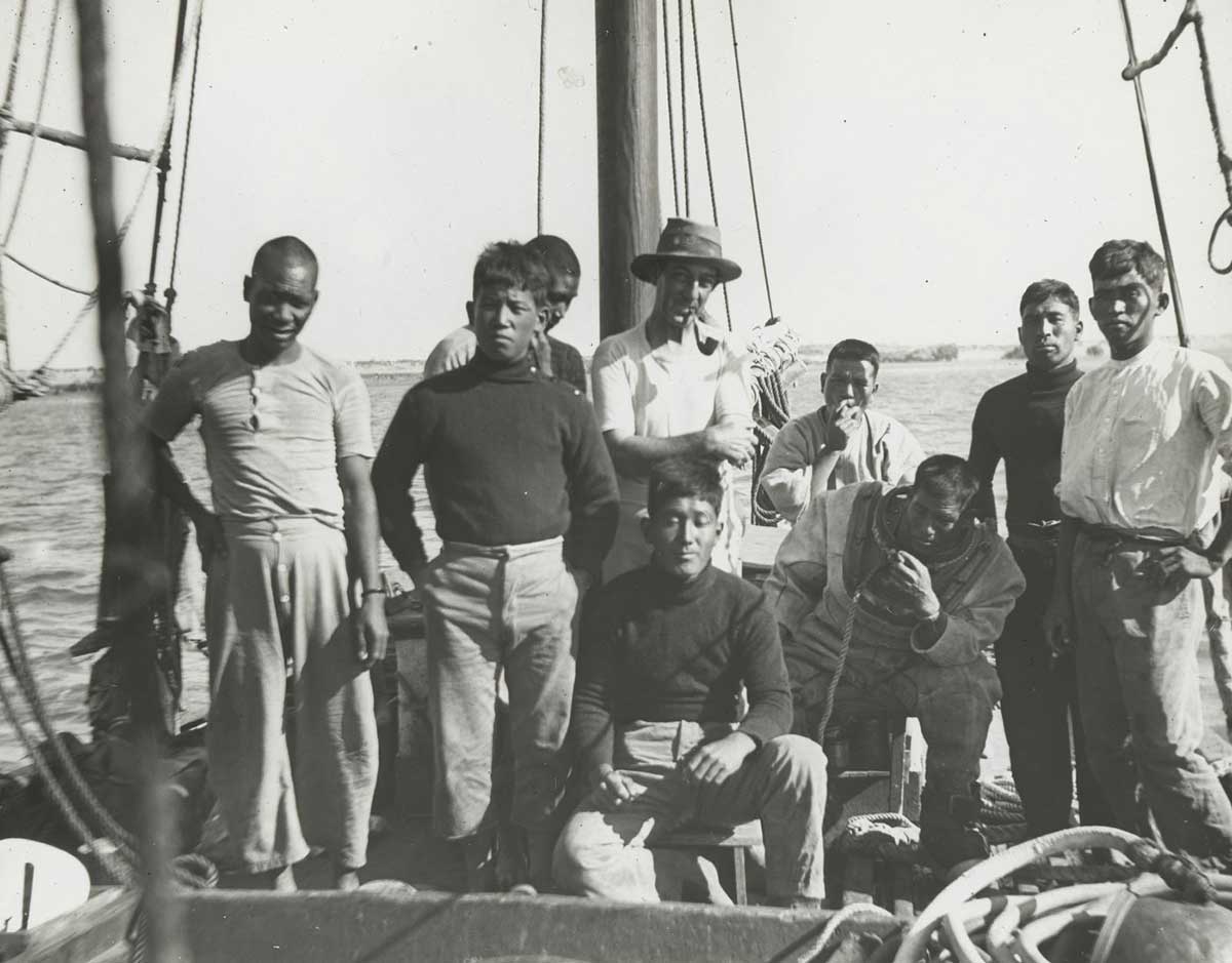 Black-and-white photo of a group of men standing on the deck of a sailing vessel.