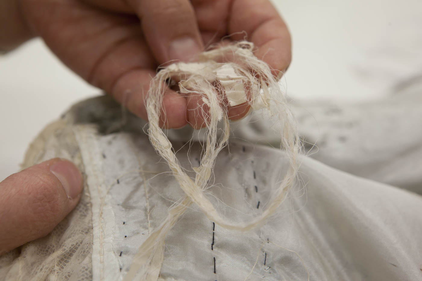 Conservator inspecting damage on the dress. - click to view larger image