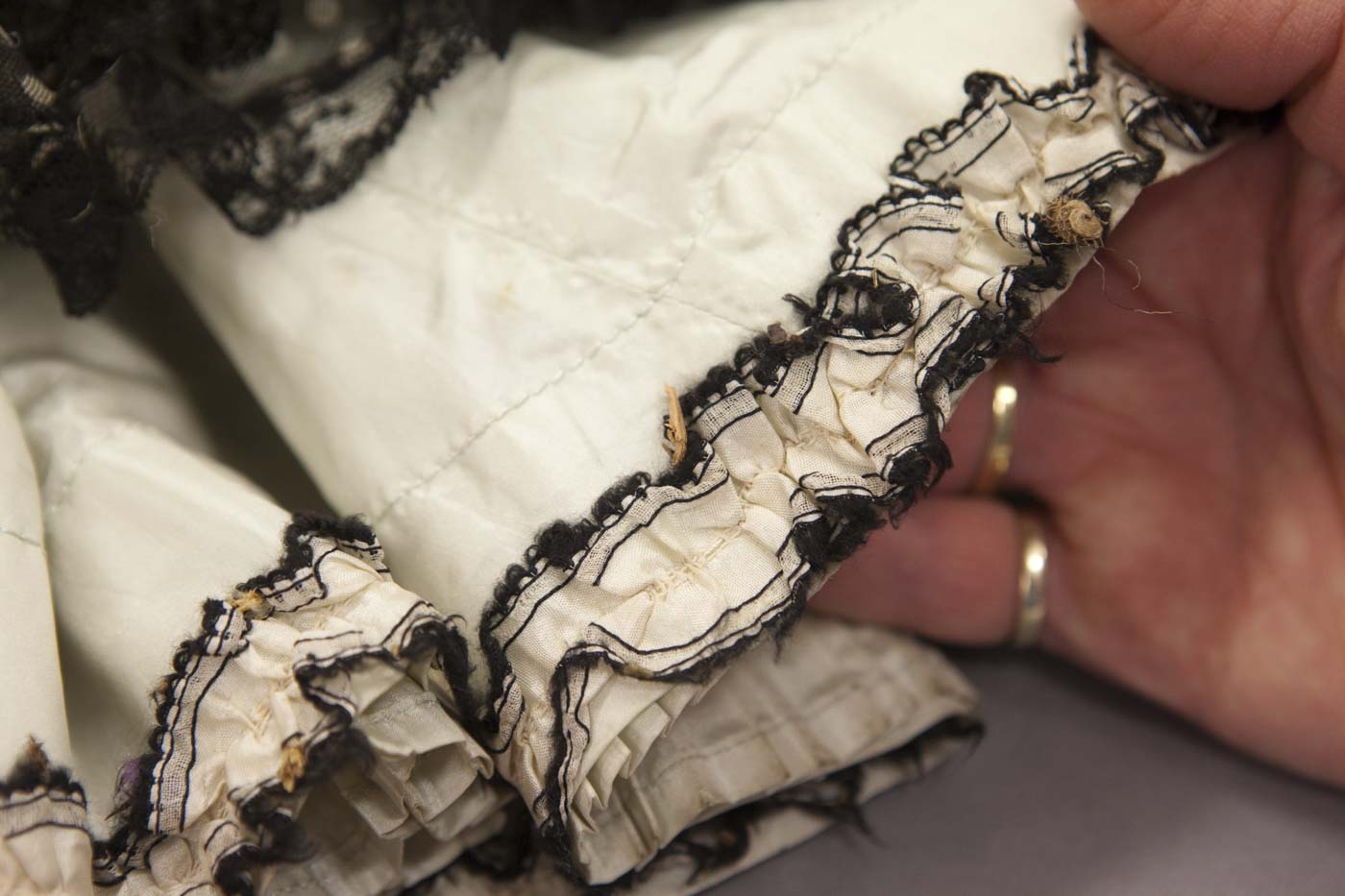 Conservator inspecting a burr in the hemline. - click to view larger image