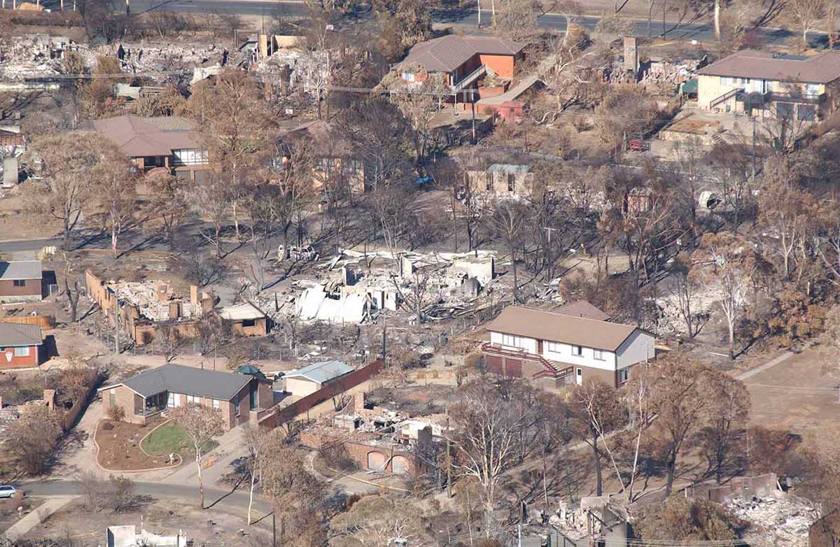 Arial view of a residential area with some houses destroyed by fire while others still stand.