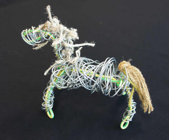 Electrical wire bent into the shape of a horse. Fencing wire is wrapped around the centre of the horse. Wool and twine have been added to form a tail and a mane.