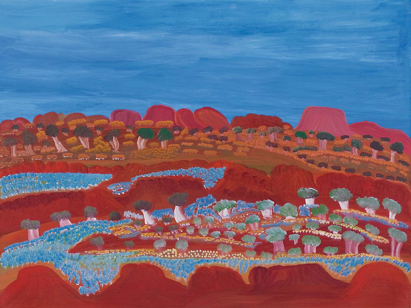 A painting on canvas with a range of orange-red rock formations lying low against a blue sky backdrop. In front of the formations are green and light brown trees and yellow-brown grass-like foliage. In the foreground are two horizontal rows of orange-red rock formations creating a valley-like appearance. The valley and some of the rock formations are covered in expanses of flowers in blue, yellow and cream as well as trees in green and beige-white. - click to view larger image