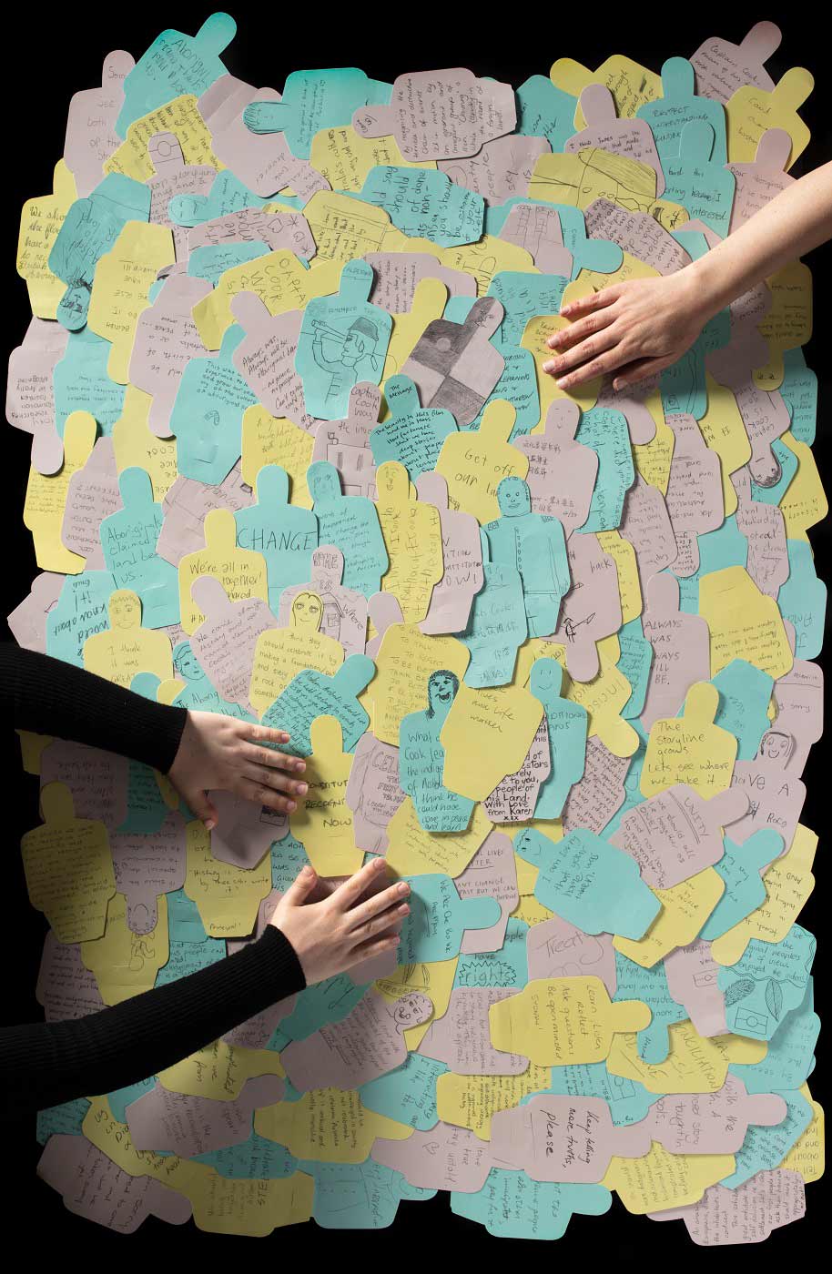 Two people sorting through a large amount of colourful paper figures featuring personalised messages. - click to view larger image