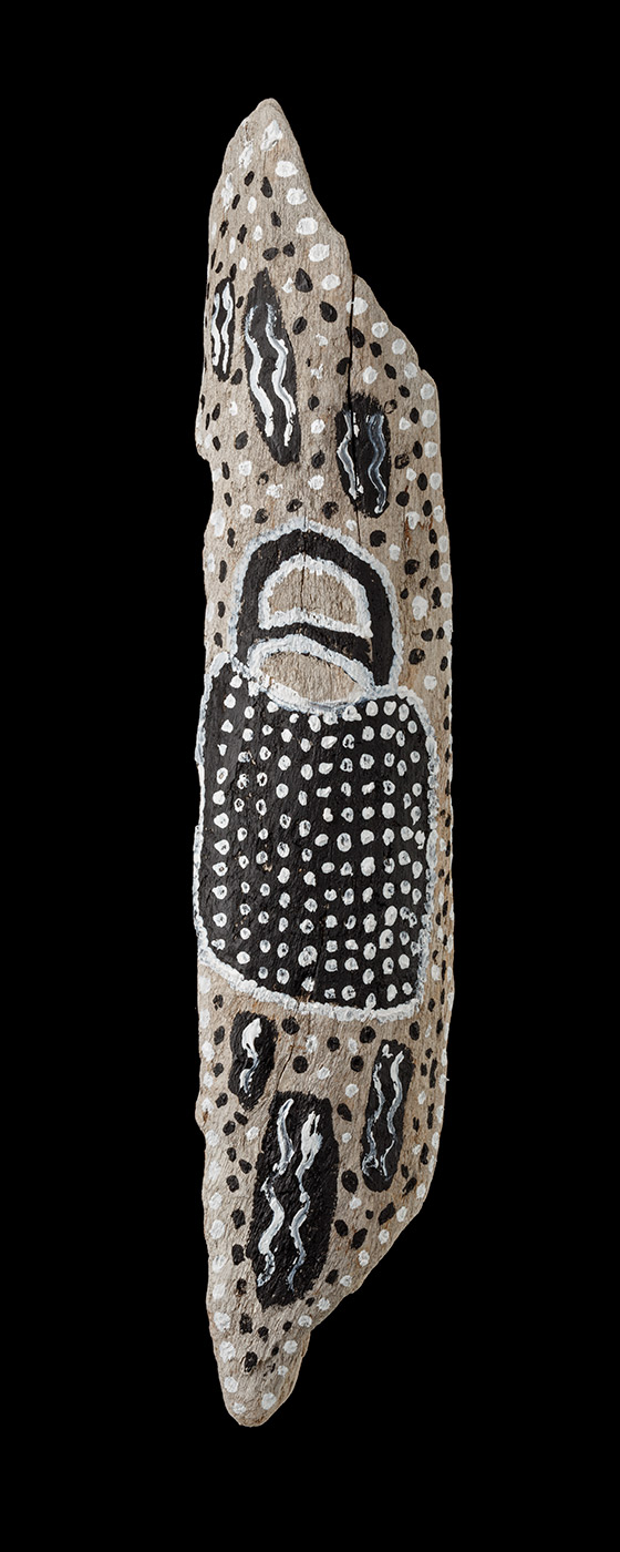An acrylic painting on driftwood featuring a black bag outlined with white dots and filled with white dots. The bag is surrounded with black and white dots, and black thick vertical painted strokes with white vertical wave lines within them. - click to view larger image