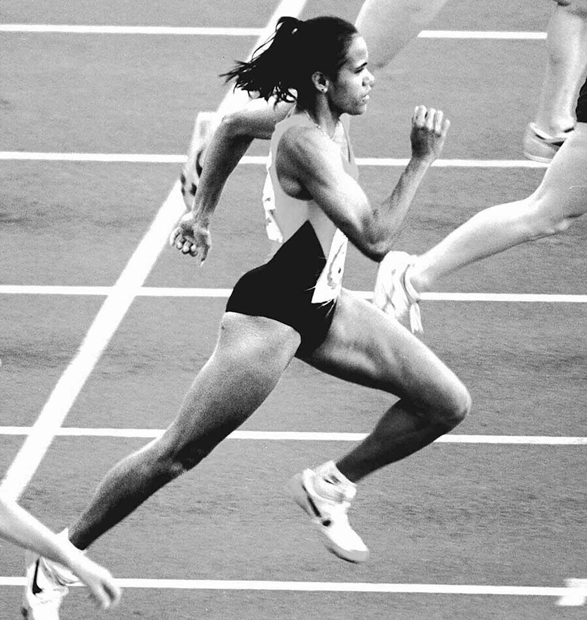 Black and white photograph of Cathy Freeman competing in a sprinting race.