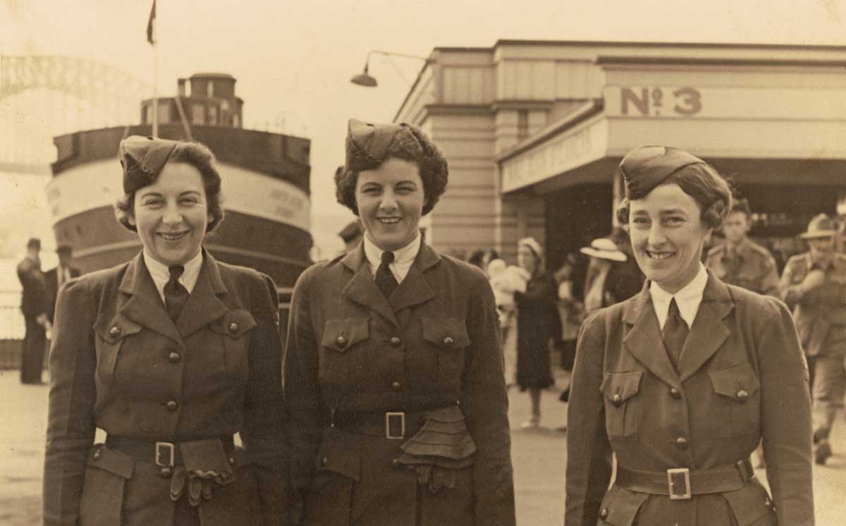Black and white photograph of three women in military uniform smiling broadly.