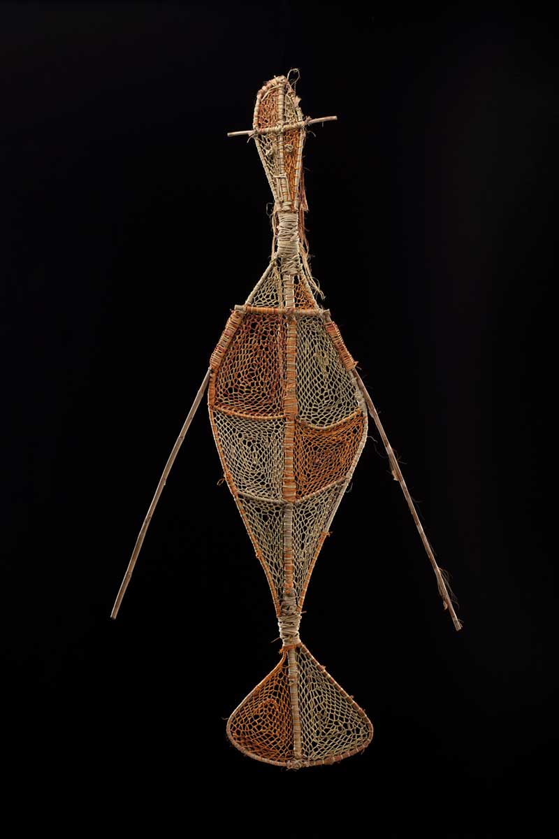 Front view of a sculpture depicting a female water spirit with a fish tail and long hair. The sculpture is made from plant materials including woven pandanus and bush cane, dyed with natural dyes, featuring bright orange and pale-yellow fibres. - click to view larger image