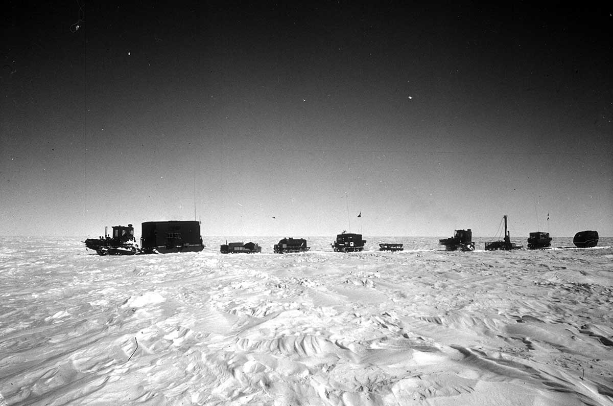 Side view of several large vehicles and sleds in a snowy landscape. - click to view larger image
