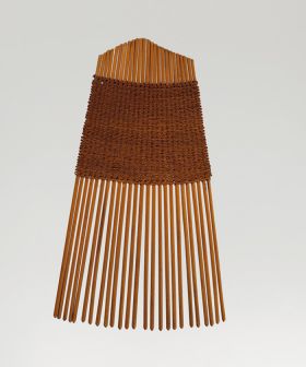 A comb made of twenty-five small sticks held together by a weave of light brown fibres.