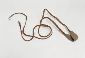 A rotation sling. The pouch and cords are made as one piece, from coconut fibres, which are intertwined with other plant material and plaited into tight and firm coils.