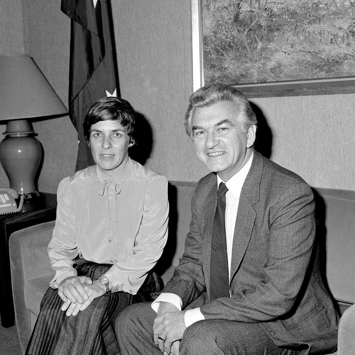 Pam O’Neill and Bob Hawke pose for the camera, seated on a couch. - click to view larger image