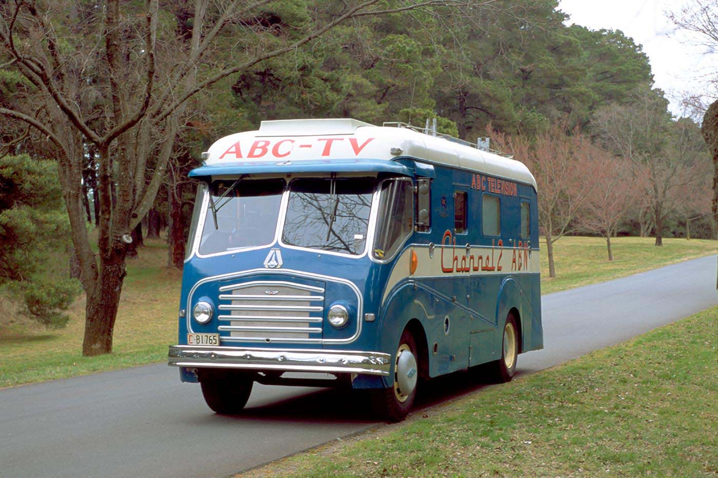 Blue van on a country road. ABC TV is painted on the front above the windscreen. - click to view larger image