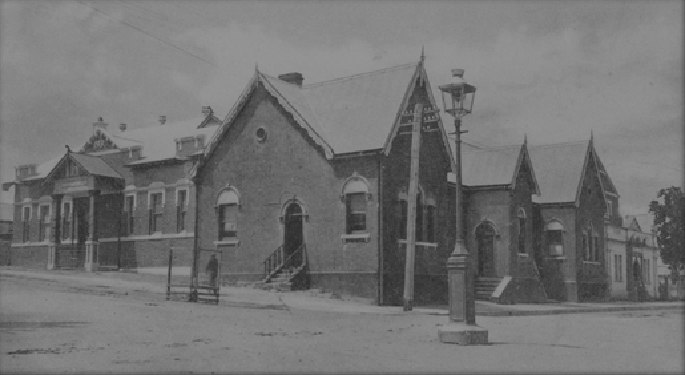 Photograph of a building on the corner of an all-but deserted street. It looks like a large, rambling church hall.