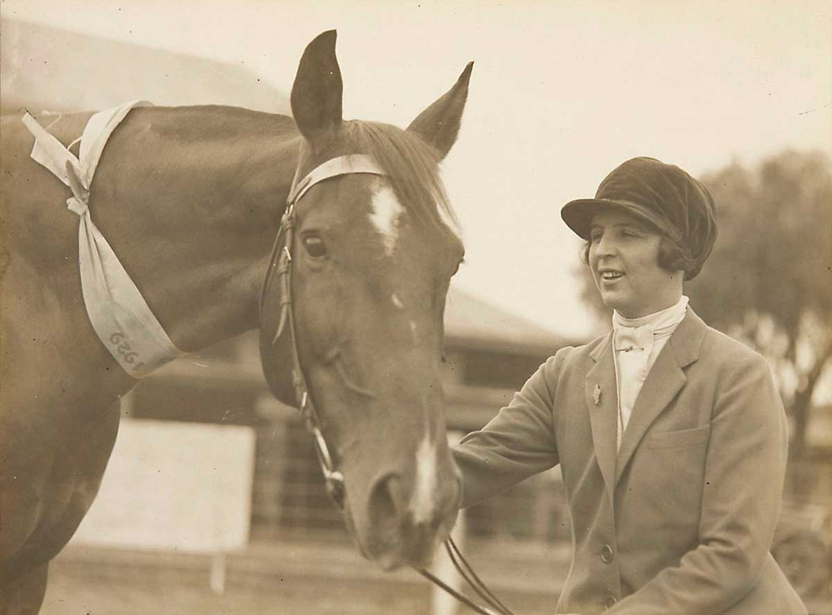 A mounted black and white photograph of Emily Roach next to mount Dungog who wears a prize ribbon around its neck.