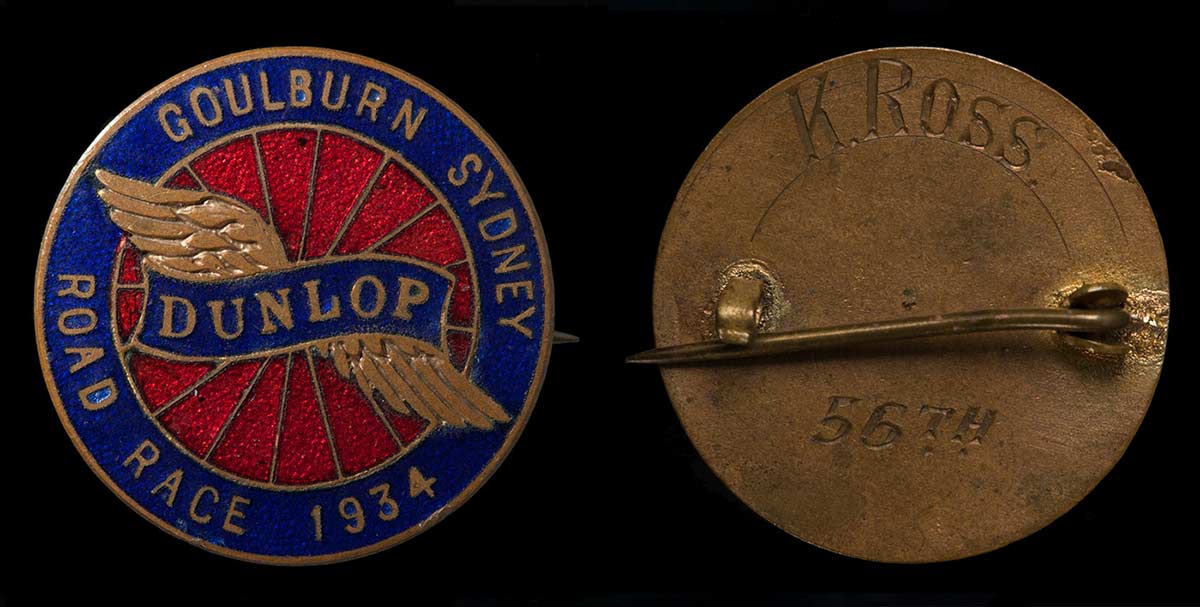 Enamelled metal medal in blue and red with gold text and an inscription on the back. - click to view larger image
