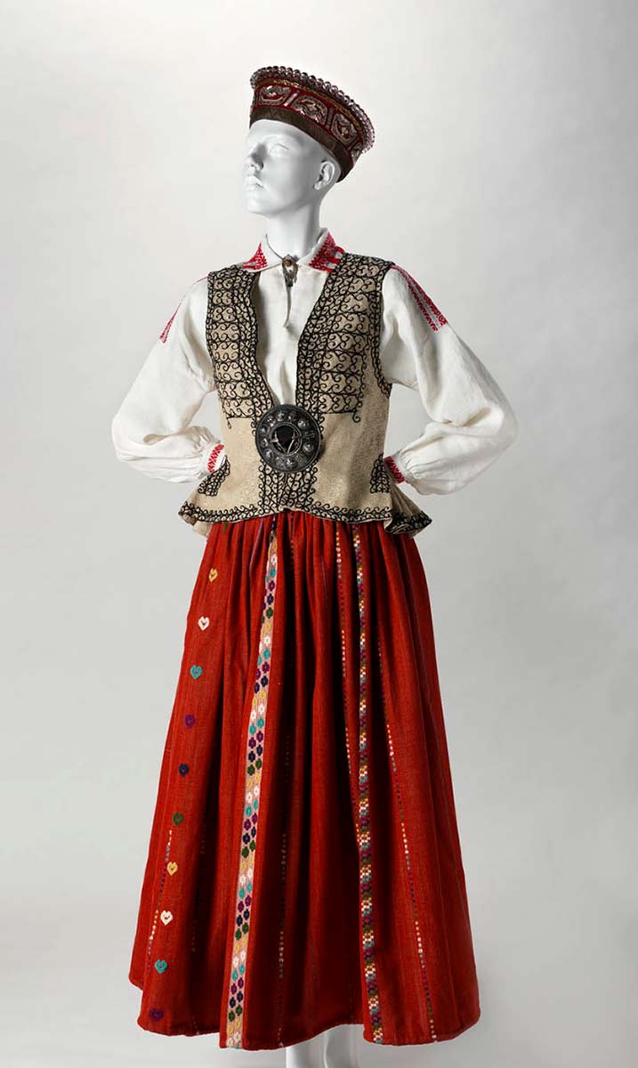A mannequin dressed in a red skirt, cream coloured, embroidered waistcoat, white linen shirt and felt cap. - click to view larger image
