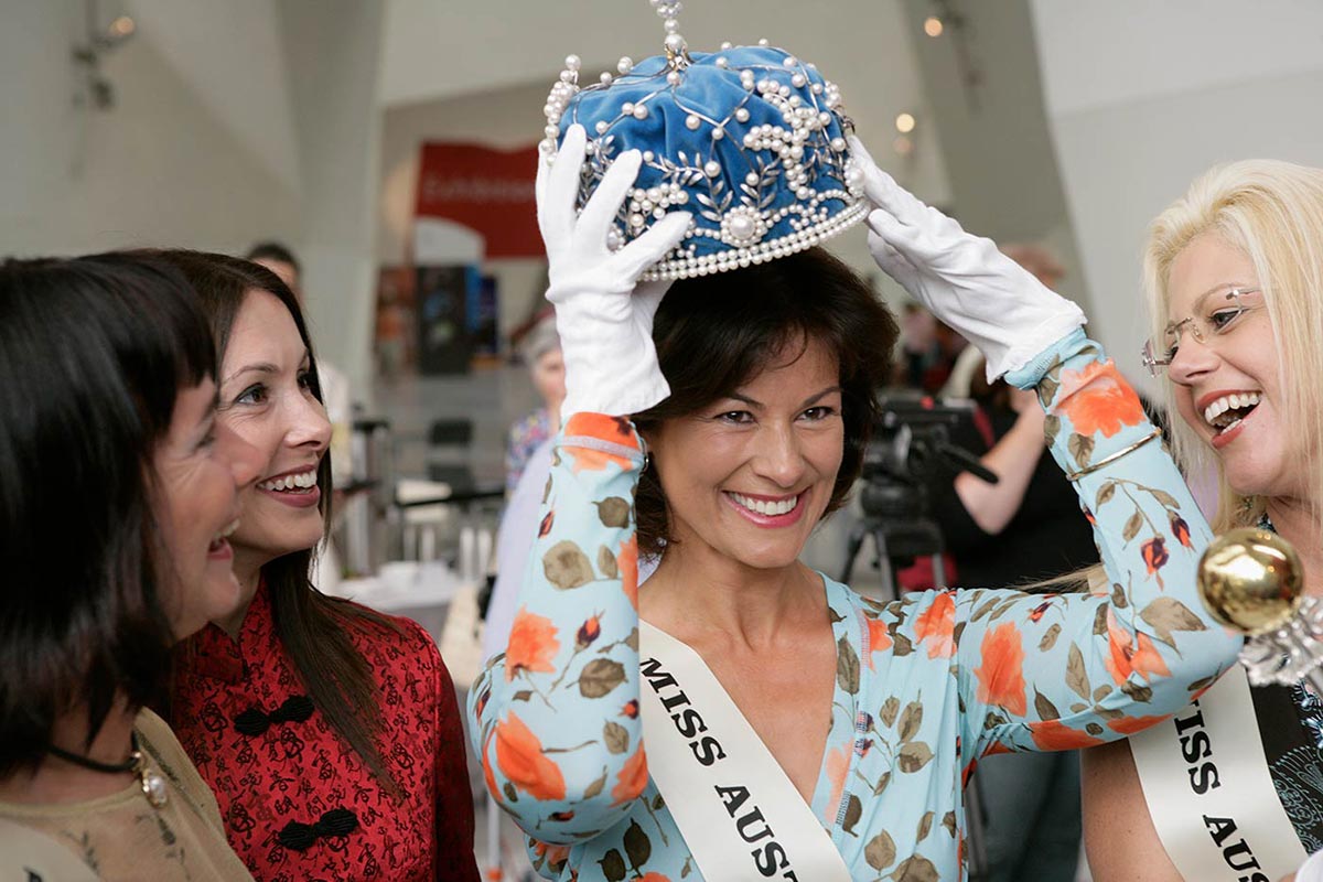 Four former Miss Australia titleholders trying on the Miss Australia crown at the National Museum of Australia. - click to view larger image