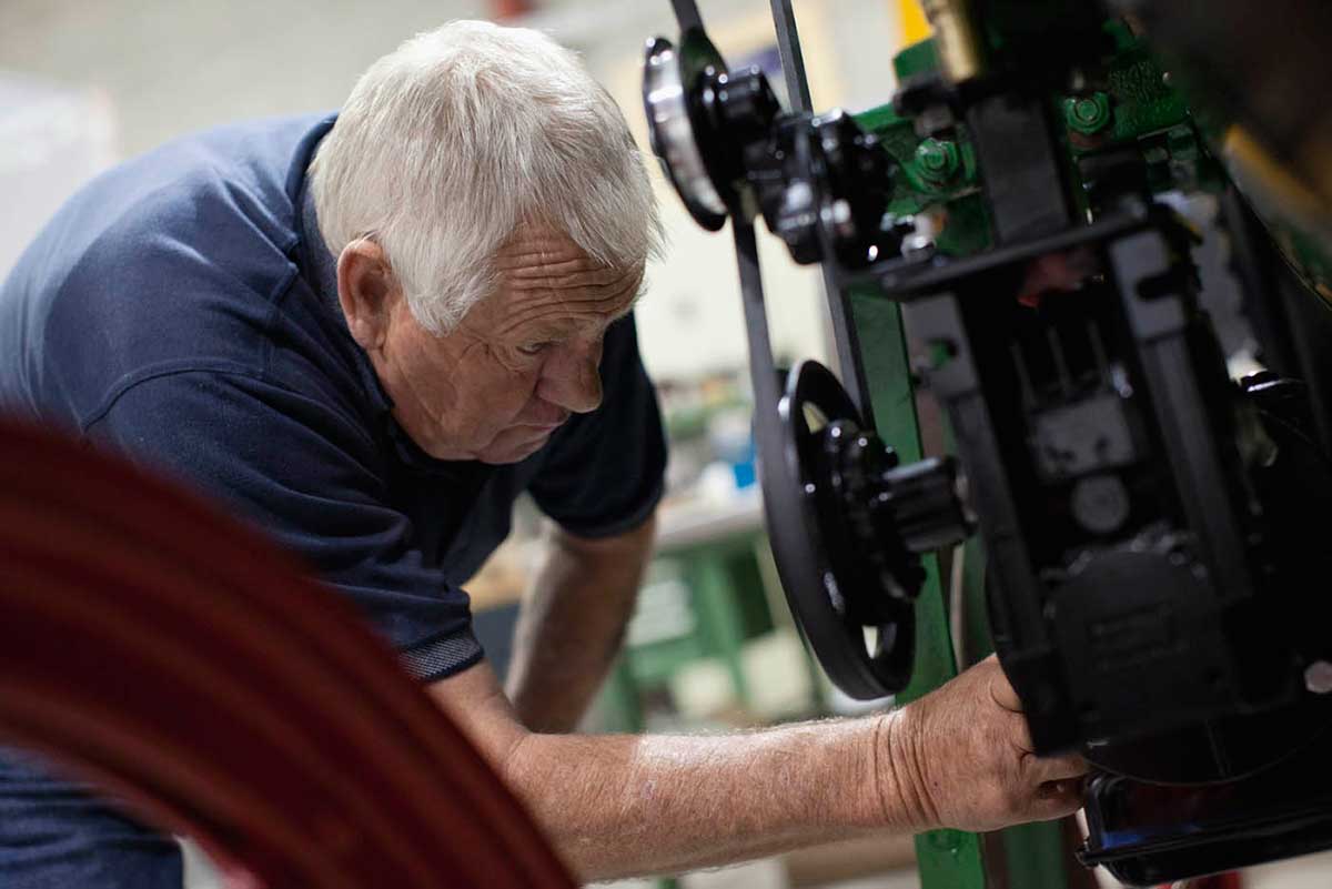 A colour photograph of a man working on an engine. - click to view larger image