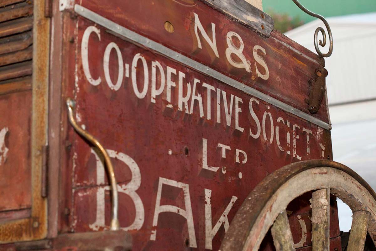 Close up of an old bakery cart showing the faded paintwork. - click to view larger image