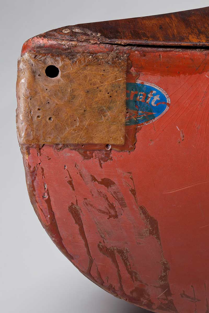 Detail of one end of a canoe with a degraded surface and repair work.  - click to view larger image
