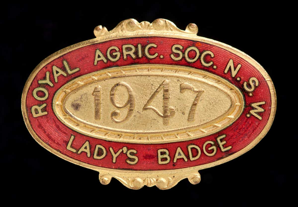 A red and gold oval badge with the words: 'Royal Agric. Soc. N.SW. Lady's Badge' around the edge and '1947' in the middle. - click to view larger image