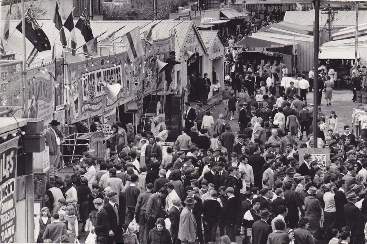 A crowd of people making their way through the sideshow alley at the Royal Adelaide Show. - click to view larger image