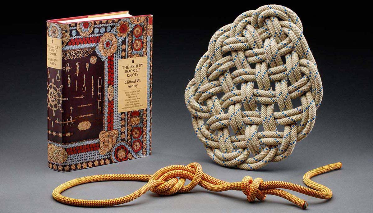 A hardbound book stands beside two rope knots. - click to view larger image