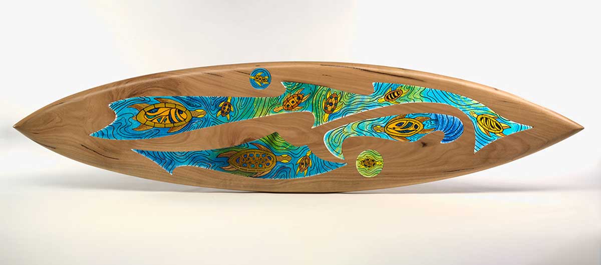 A sculpture made of carved wood in the shape of a surfboard inset with infused coloured glass. - click to view larger image
