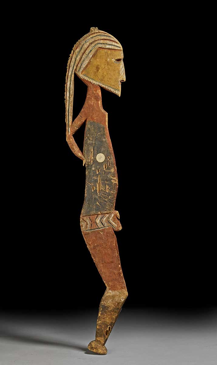 Human figure carved in profile from a flat piece of wood. Painted in red, black, yellow, and white patterns. - click to view larger image