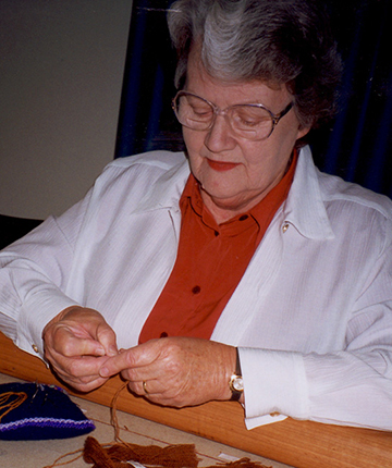 Embroiderer working on the Crimson Thread of Kinship embroidery.