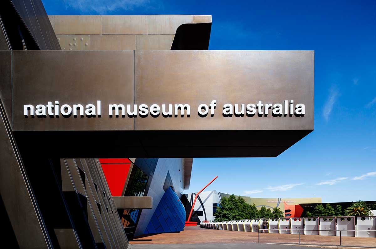 A view of the Museum's entrance with a large sign which spells 'National Museum of Australia' featuring above.