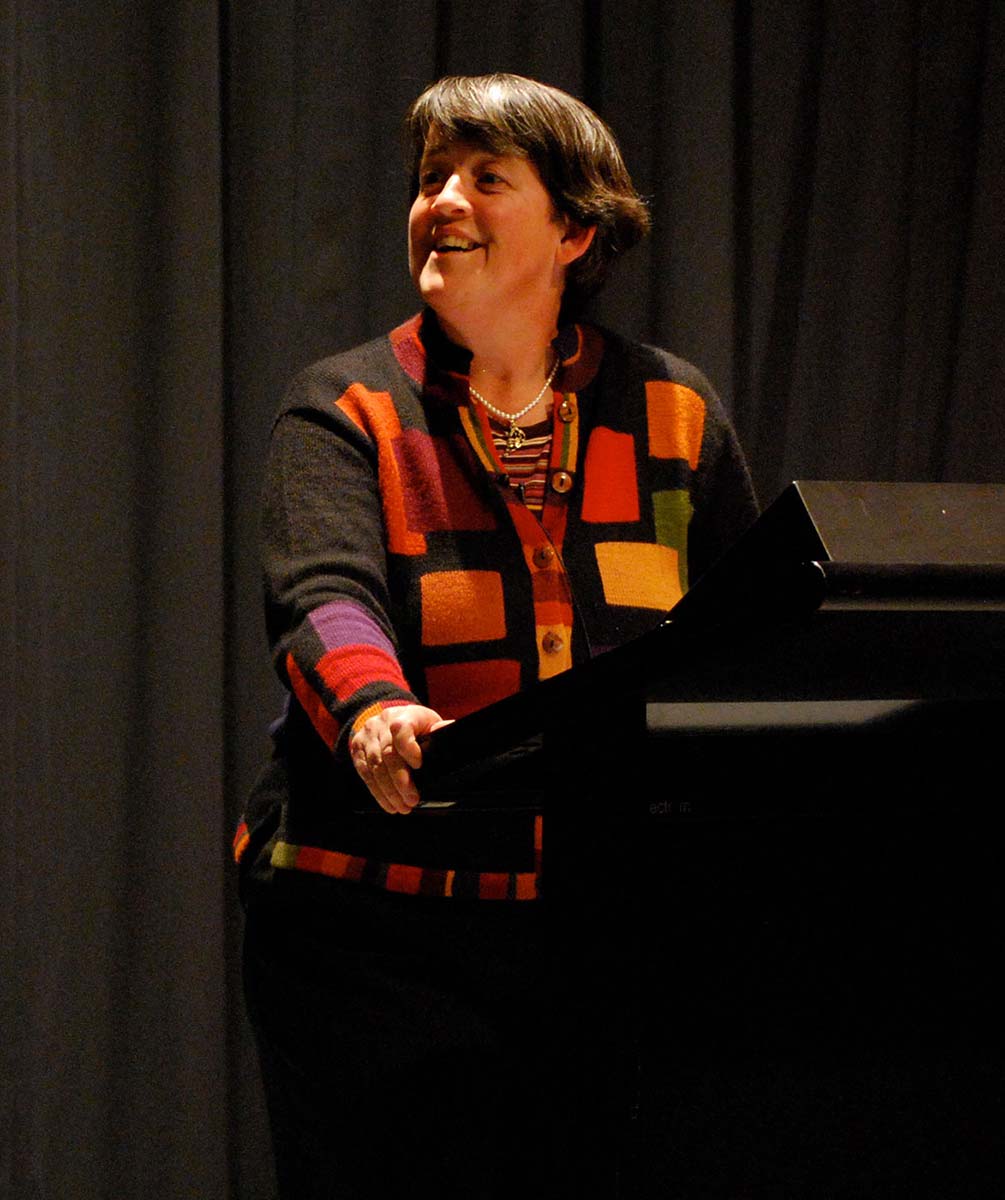 A woman stands at a lectern on stage. - click to view larger image