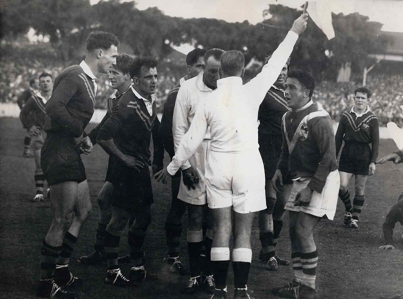 Photo of 1951 Test match between Australia and France. Frenchman Puig Aubert and Australia's Clive Churchill plead their cases while Referee Tom McMahon takes the linesman's report