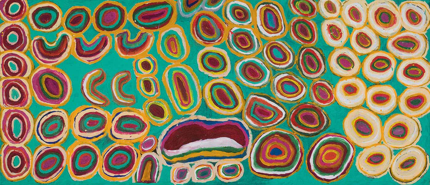 A painting on brown linen with many concentric circles outlined in yellow with red and green tones inside on a background of aqua green. In the lower centre of the painting is a dark pink toned shallow crescent shape with a white-cream outline. To the upper left of it are five C shapes in green, orange, red, white, pink and yellow stripes. At the left edge there are six concentric circles in a vertical line. The section to the right of the painting has concentric circles in lines with cream and yellow outer section and green, yellow orange and pink in the centre.