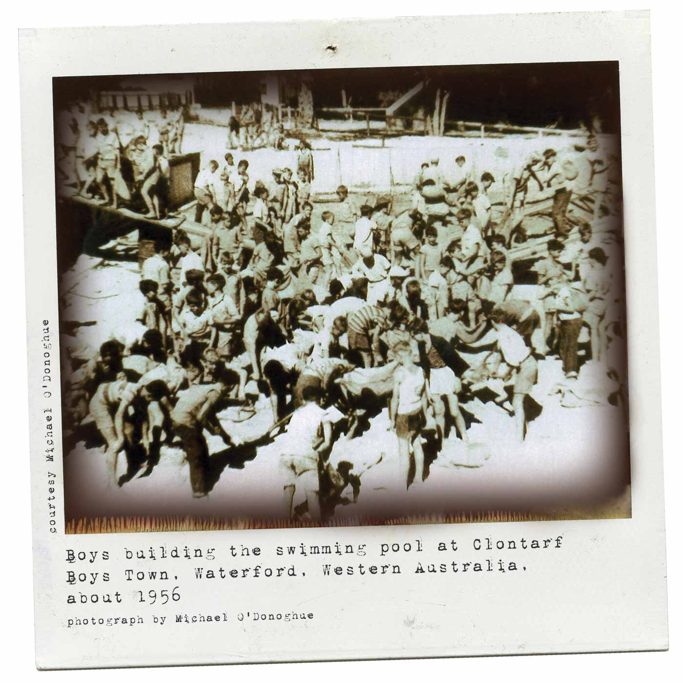 Polaroid photograph showing a large group of boys busy on a buliding site. Many dig in the foreground and others walk up a plank on the left. Typewritten text below reads 'Boys building the swimming pool at Clontarf Boys Town, Waterford, Western Australia, about 1956. Photograph by Michael O'Donoghue'. - click to view larger image