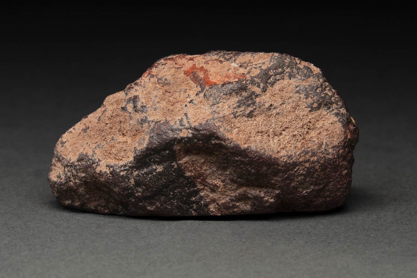Piece of rock featuring a rough surface and variations in ochre tones. - click to view larger image