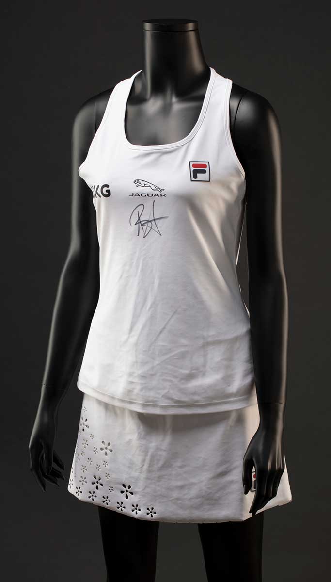 A white Fila 'Trailblazer' tennis outfit consisting of a tank top and skort. The front features a 'UKG' logo and 'JAGUAR' logo, as well as a handwritten signature in black ink. The skort has a laser cut scalloped hem and floral decoration at the front and side. - click to view larger image