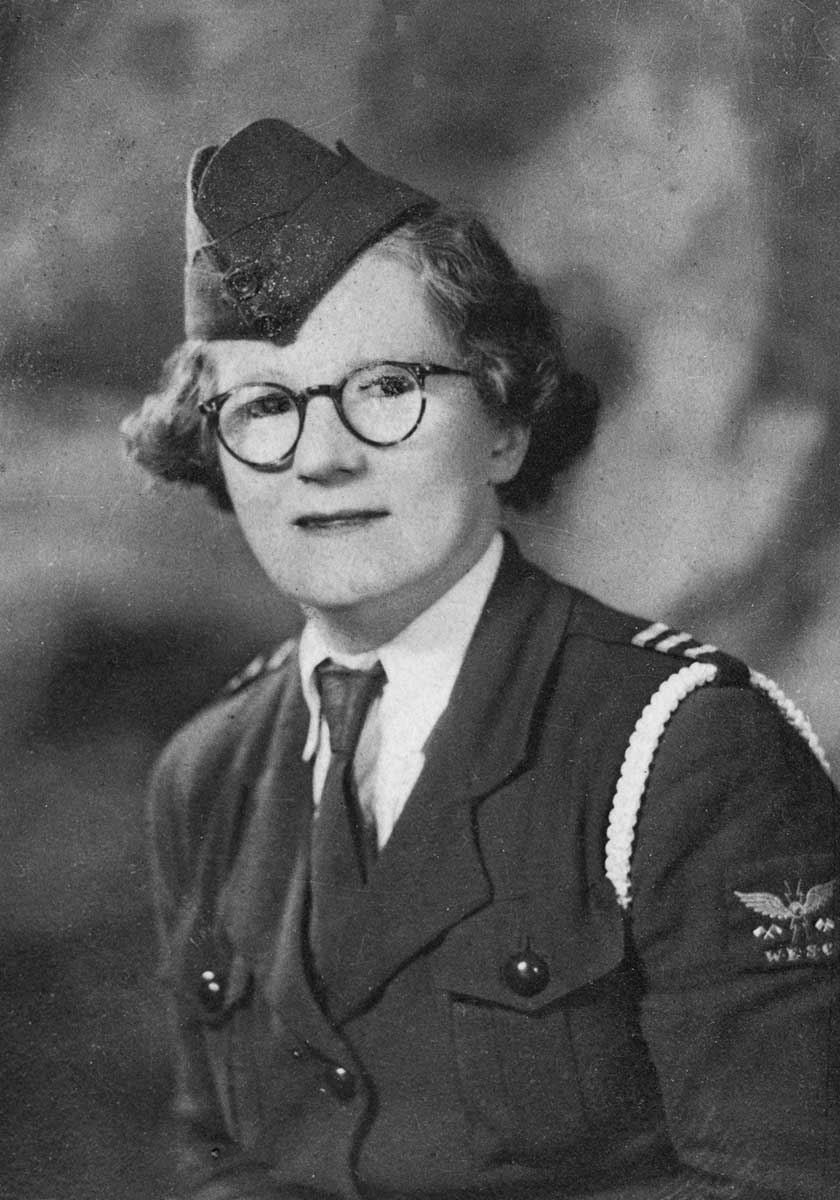 Black and white photograph portrait of a woman wearing a military uniform with an embroidered patch bearing the initials 'WESC'.  - click to view larger image