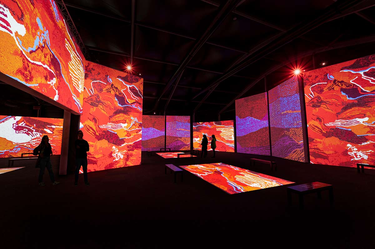 Digital render of people interacting with an exhibition space, which features multiple digital screens on the walls and floor.